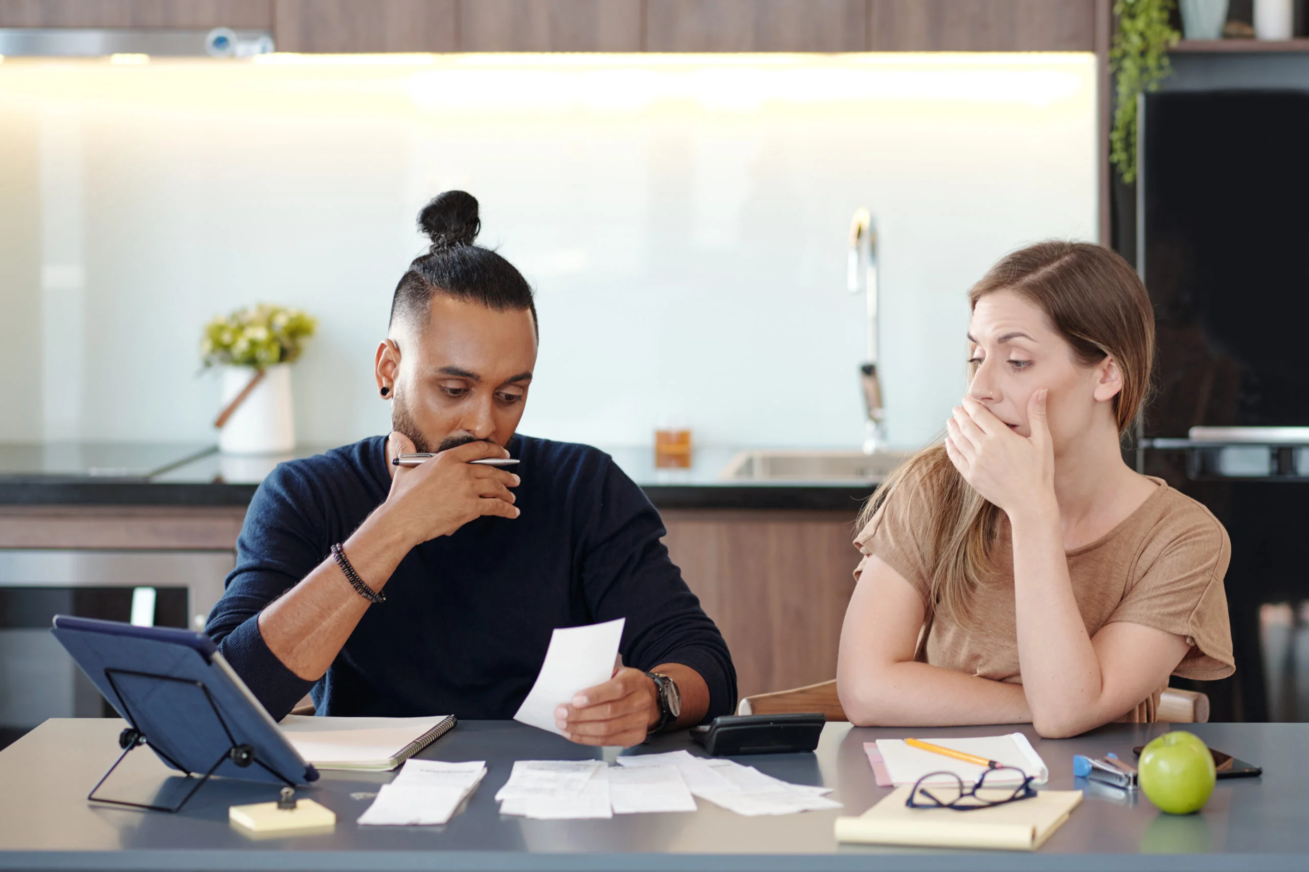 a man and woman sitting at a table with papers and a laptop