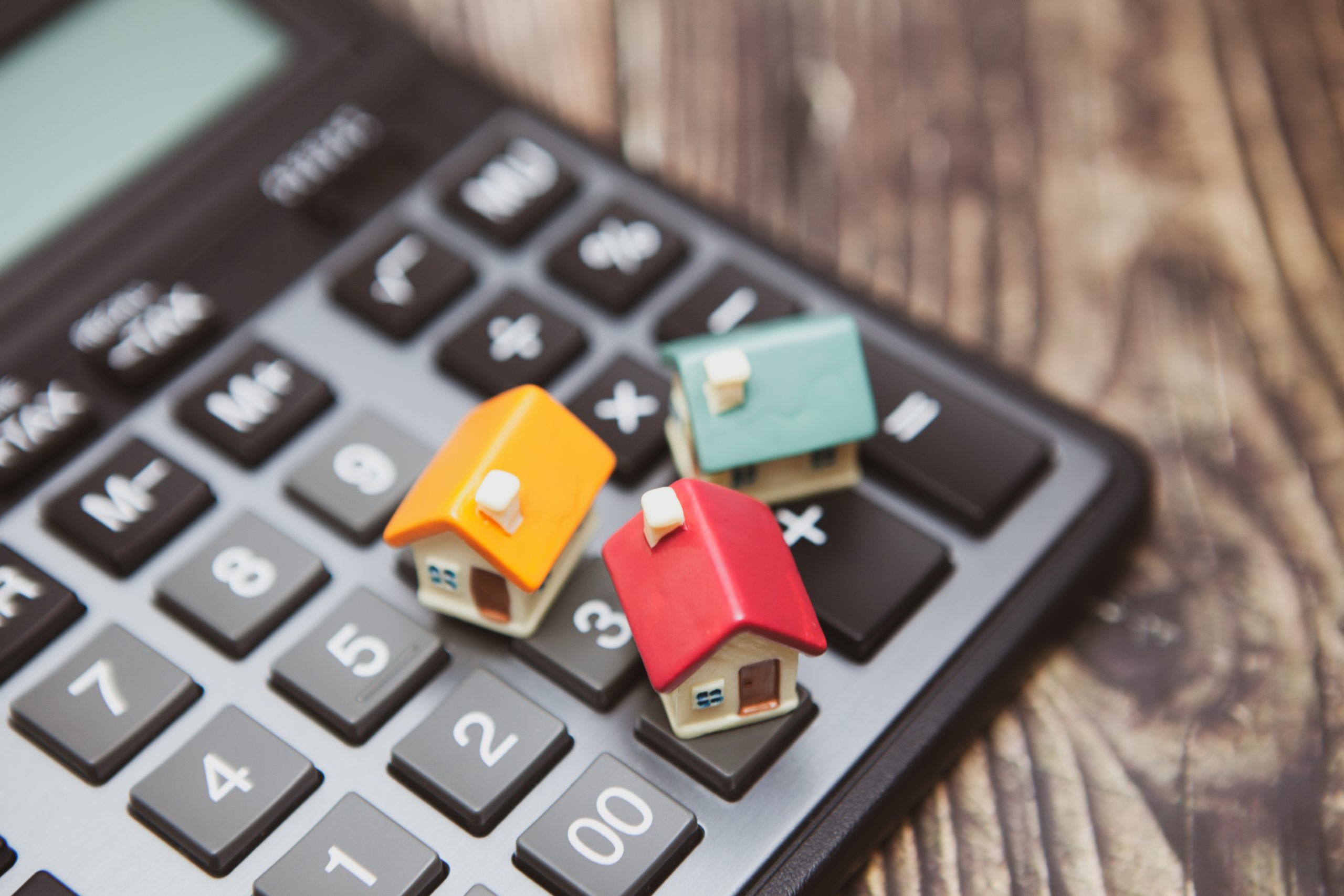 A calculator and several colored houses. The concept of buying a home on credit or a mortgage
