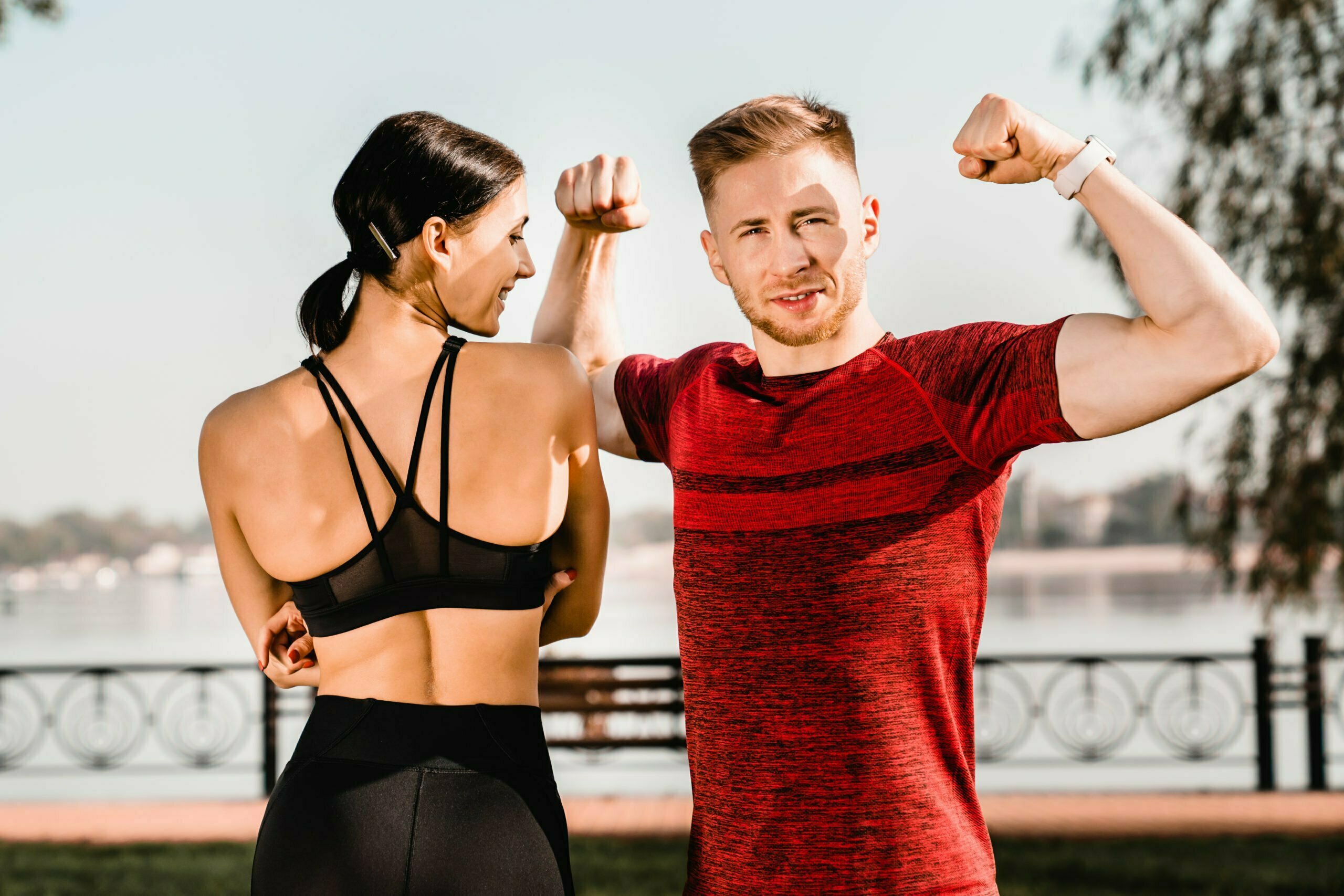Strong fit young couple wearing fitness outfit in city park